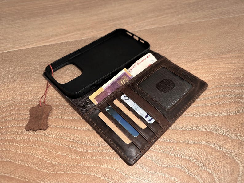 A brown leather wallet with a black case and various cards and cash inside is placed on a wooden surface.