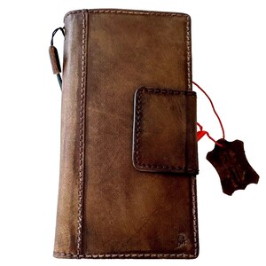May include: A brown leather wallet with a flap closure and a stitched design. The wallet has a small pocket on the front and a leather tag attached to it.