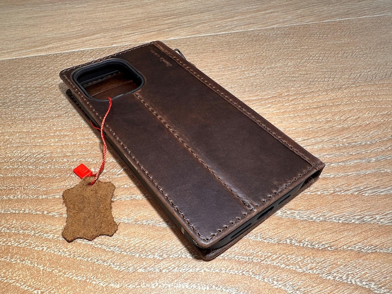 A brown leather wallet is placed on a wooden surface, with a red tag attached to it.