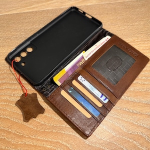 A brown wallet with a black case and various cards is placed on a wooden surface.