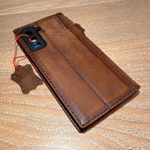 A brown leather wallet is placed on a wooden surface, with a small tag attached to it.