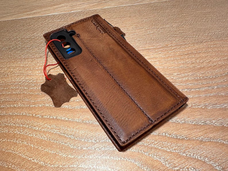 A brown leather wallet is placed on a wooden surface, with a small tag attached to it.
