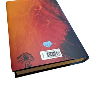 K&ouml;nnte beinhalten: Der hintere Umschlag eines Buches mit einem roten, orangen und gelben Farbverlauf als Hintergrund. Der Buchtitel "MAY" und das Jahr "2024" sind in schwarzer Schrift gedruckt. Ein L&ouml;wenzahn mit Samen, die im Wind fliegen, ist in schwarzer Tinte in der linken unteren Ecke gedruckt. Die ISBN-Nummer und der Barcode sind in der rechten unteren Ecke gedruckt. Der Text "MADE IN USA" ist unter dem Barcode gedruckt.