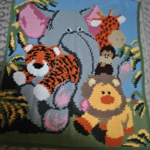 May include: A handmade crochet blanket featuring a jungle animal theme. The blanket showcases a gray elephant, orange tiger, yellow lion, and giraffe, surrounded by green foliage against a blue background. The blanket is bordered with green.