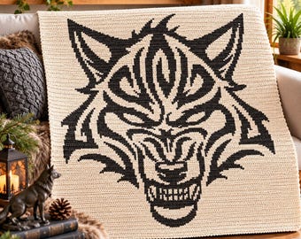 May include: A cream-colored crochet blanket featuring a large, centered black graphic of a snarling wolf head. The design is created with intricate yarn stitches, showcasing the wolf's pointed ears, sharp teeth, and detailed facial markings.