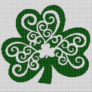 May include: A green and white shamrock design. The shamrock is a three-leaf clover with intricate white scrollwork filling the leaves. The background is a grid of small squares.