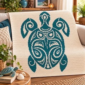 Op de afbeelding: Een crèmekleurige gehaakte deken met een groot, centraal geplaatst zeeschildpadmotief in een diepe kleur blauwgroen. Het schildpadontwerp bestaat uit ingewikkelde, gestileerde geometrische patronen en vloeiende lijnen voor een sterk contrast.