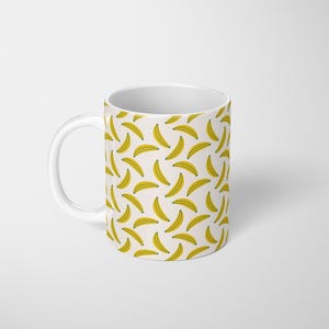 Puede incluir: Taza de cer&aacute;mica blanca con un patr&oacute;n repetido de pl&aacute;tanos amarillos sobre un fondo crema. La taza tiene un asa blanca y un dise&ntilde;o sencillo. Ideal para caf&eacute; o t&eacute;, esta taza a&ntilde;ade un toque divertido.