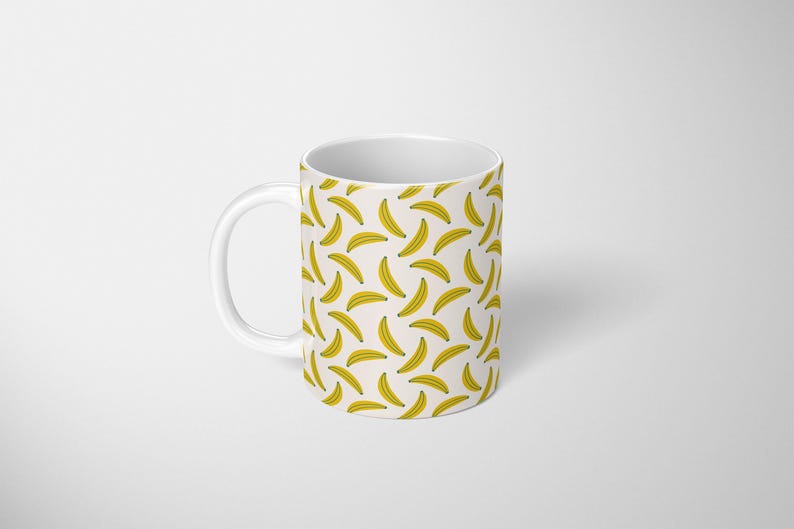Puede incluir: Taza de cer&aacute;mica blanca con un patr&oacute;n repetido de pl&aacute;tanos amarillos sobre un fondo crema. La taza tiene un asa blanca y un dise&ntilde;o sencillo. Ideal para caf&eacute; o t&eacute;, esta taza a&ntilde;ade un toque divertido.