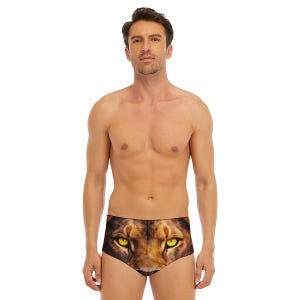 Könnte beinhalten: Badehose mit Löwengesicht-Print. Die Badehose ist braun und schwarz, mit einem detaillierten Bild der Augen und der Nase des Löwen. Das Model steht und schaut nach vorne. Die Badehose ist im Low-Waist-Stil.