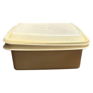 May include: A rectangular food storage container with a light brown base and a translucent, off-white lid. The lid has a slightly raised edge and fits snugly on the container. The container is made of plastic.