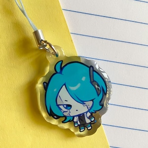 May include: A clear acrylic charm featuring a cartoon character with blue hair and a black and white outfit. The charm has a light blue lanyard attached with a silver clasp. The character has a determined expression.