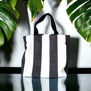 May include: A black and white striped tote bag with fabric handles. The bag is made of a thick, durable material and has a spacious interior.