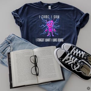 Könnte beinhalten: Ein marineblaues T-Shirt mit einer pinkfarbenen Robotergrafik und dem Text "Ich kam, ich sah. Ich vergaß, was ich tat."