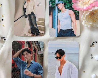 May include: Four photo cards featuring a man in different outfits and poses. The photos are printed on white card stock and have a white border. The man is wearing a white shirt, a white tank top, a blue shirt, and a white shirt with a white tank top underneath.