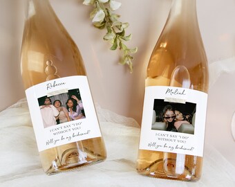 May include: Two bottles of rose wine with personalized labels featuring photos and the text "I can't say 'I do' without you. Will you be my bridesmaid?"
