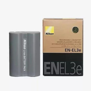 May include: A grey Nikon Li-ion battery pack and its box. The box is tan and black with the Nikon logo and the text "EN-EL3e". The battery pack is cylindrical and has the Nikon logo and text on its side.