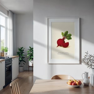 May include: Framed art print featuring a vibrant illustration of a beet with green leaves and a sliced portion. The text reads, "Rooted in nature's goodness, beets nourish the body and soul." The artwork is displayed in a bright, modern kitchen setting.