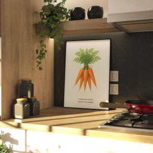 May include: A framed print featuring a watercolor illustration of a bundle of carrots with green tops. The print is displayed in a kitchen setting, alongside jars, a plant, and a red pan. The text on the print reads: "Crunchy and colorful, nature's sweet delight."