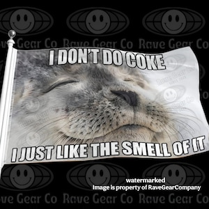 May include: A white rectangular flag attached to a white pole featuring a photographic print of a grey seal with its eyes closed. The text I DON'T DO COKE is printed in black at the top and I JUST LIKE THE SMELL OF IT at the bottom.