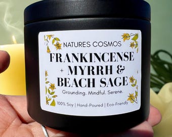 May include: A black candle tin with a white label featuring the text "FRANKINCENSE + MYRRH & BEACH SAGE". The label also includes the text "Grounding. Mindful. Serene." and "100% Soy | Hand-Poured | Eco-Friendly."