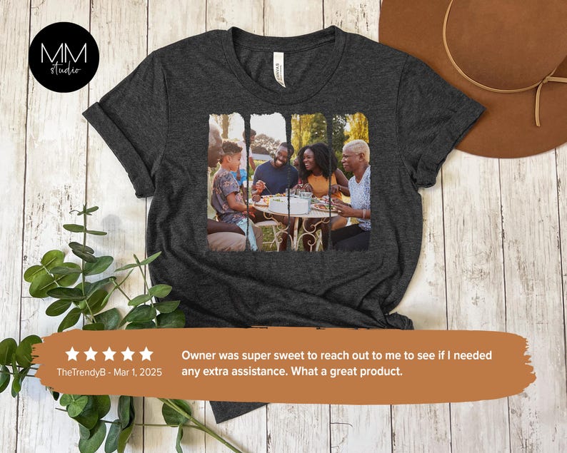May include: A dark gray t-shirt with a photo of a family of four sitting at a table outdoors. The photo is printed in a rectangular shape on the front of the shirt.