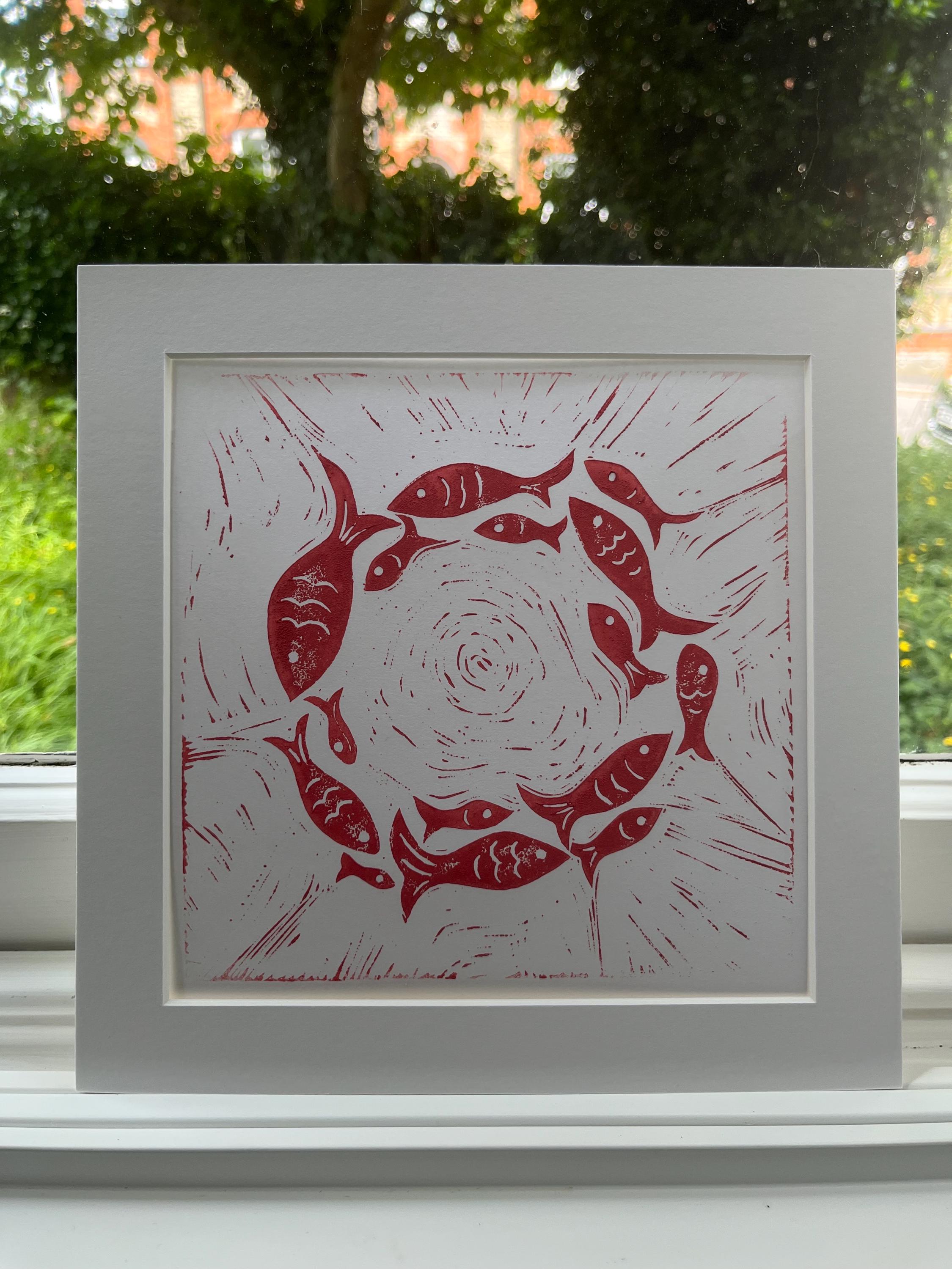 Circle of fish linoprint in dark pink.