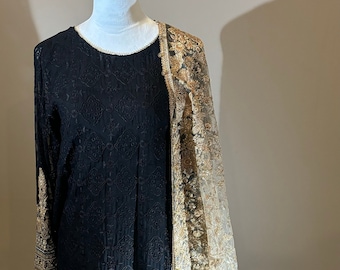 May include: A black long-sleeved dress with gold embroidery and a matching gold sheer dupatta. The dress has a round neckline and a flared skirt.