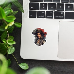 May include: A sticker featuring a woman with dark hair wearing a red and black pirate hat and a black and brown pirate costume.
