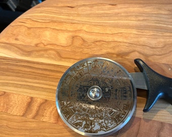 Star Wars calendar themed Stainless steel pizza cutter with ergonomic handle. Disc of pizza cutter is engraved with Star Wars themed image