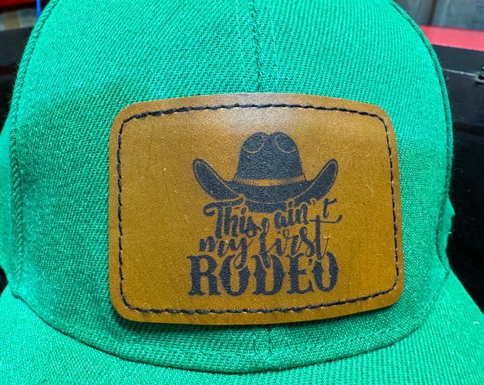 This ain’t my first rodeo laser engraved leather patch hat. Green cap with Velcro adjustable strap.