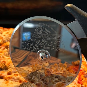 Stainless steel pizza cutter with ergonomic handle. Disc of pizza cutter is engraved