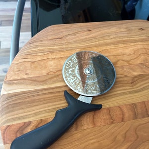 Stainless steel pizza cutter with ergonomic handle. Disc of pizza cutter is engraved
