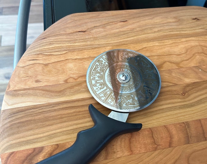 Stainless steel pizza cutter with ergonomic handle. Disc of pizza cutter is engraved