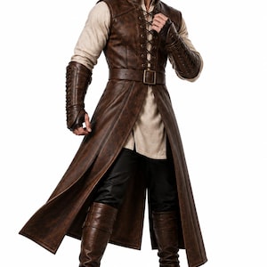 May include: A long brown sleeveless coat with a front lace-up closure and a matching belt, worn over a beige long-sleeved shirt and black trousers. The outfit includes brown forearm bracers and tall brown boots with buckle details.