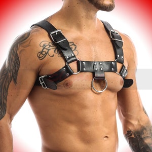 May include: Black leather harness with silver buckles and a large silver ring. The harness has a studded design.
