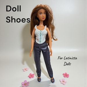 May include: A doll dressed in a white crochet top with teal detailing, dark blue trousers, and blue shoes. The doll has long brown hair and is surrounded by pink flowers. Text on the image reads "Doll Shoes" and "For Latinista Dolls."