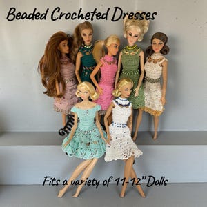 May include: A group of dolls wearing beaded crocheted dresses in various colors, including pink, green, and white. The dresses fit 11-12" dolls. The image includes the text "Beaded Crocheted Dresses" and "Fits a variety of 11-12" Dolls."