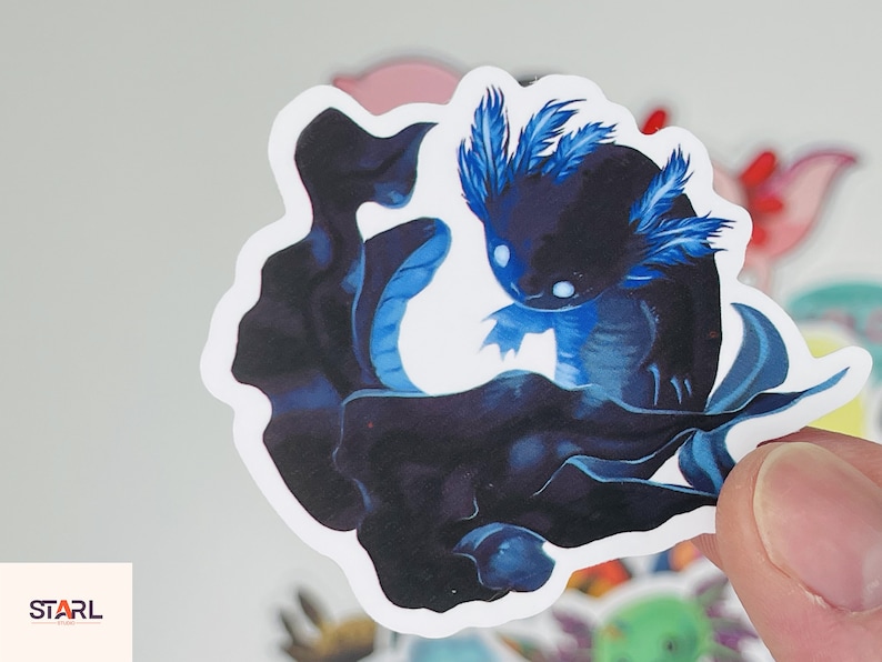 Op de afbeelding: Een sticker met een zwarte en blauwe axolotl met blauwe gevederde kieuwen. De axolotl zwemt in een donkerblauwe werveling.