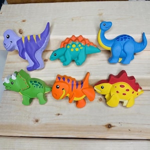 May include: A set of six colorful dinosaur figurines. The collection includes a purple T-Rex with yellow stripes, a teal Stegosaurus, a blue long-necked Brachiosaurus, a green Triceratops, an orange dinosaur, and a yellow dinosaur with red plates.