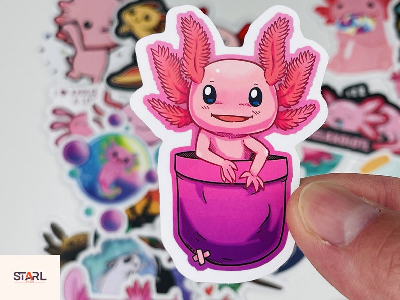 Op de afbeelding: Een roze axolotl met gevederde kieuwen kijkt uit een roze zak. De axolotl heeft een brede glimlach en grote, ronde ogen. De zak is op een witte achtergrond.