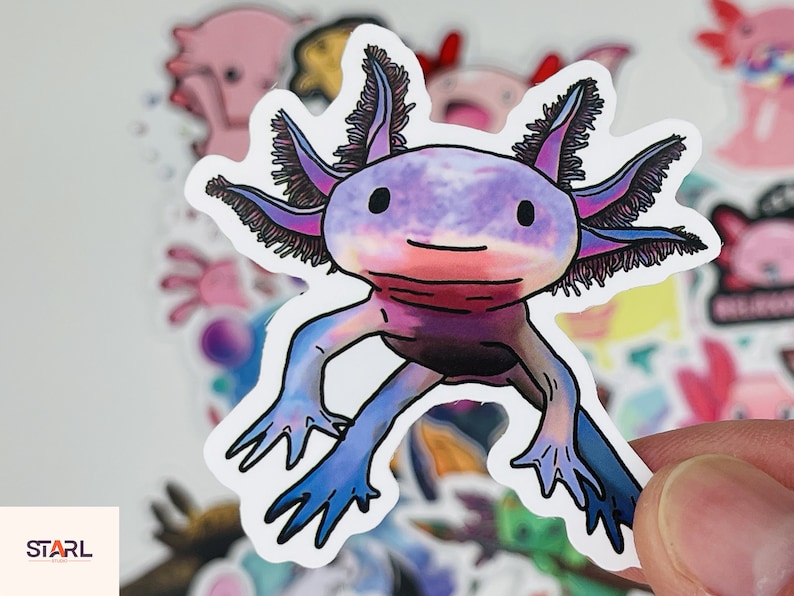 Op de afbeelding: Een sticker met een cartoon-axolotl in een paars, roze en blauw kleurenschema. De axolotl heeft een vriendelijke uitdrukking en is afgebeeld met gevederde kieuwen.