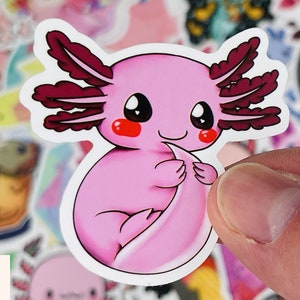 Op de afbeelding: Een roze axolotl-sticker met rode kieuwen en grote, zwarte ogen. De axolotl houdt zijn staart in zijn voorpoten.