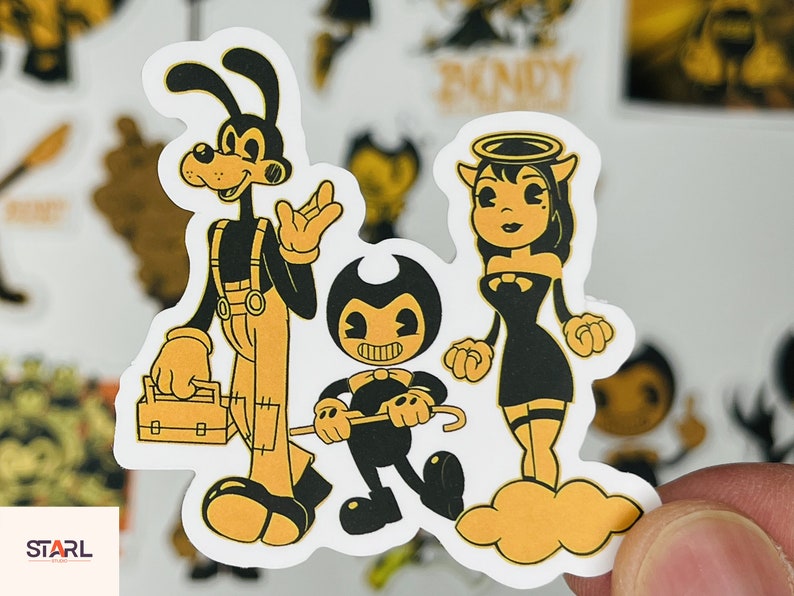 May include: A set of three cartoon character stickers featuring a black and white dog with a tool belt, a black and white devil with a halo, and a black and white cartoon character with a bow tie. The stickers are on a white background.
