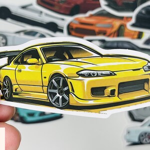 Puede incluir: Una pegatina de coche amarilla con una ilustraci&oacute;n detallada de un coche deportivo amarillo con detalles negros. El coche tiene un aler&oacute;n negro y ruedas negras. La pegatina es perfecta para los entusiastas de los coches y los coleccionistas.