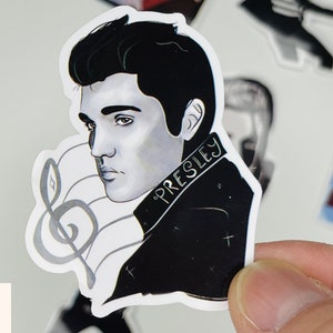 May include: Black and white illustration of Elvis Presley with a treble clef in the background. The sticker has the text "PRESLEY" on it.