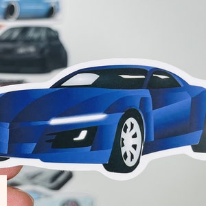 Puede incluir: Una pegatina de coche deportivo azul con un contorno blanco. El coche tiene un parabrisas negro y faros negros. La pegatina es perfecta para a&ntilde;adir un toque de estilo a cualquier superficie.