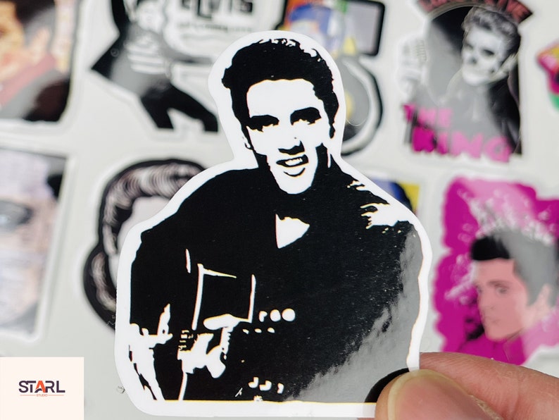 May include: Black and white sticker of a man playing a guitar. The man has a black silhouette with a white face and hair. The guitar is also a black silhouette with white details. The sticker is on a white background.