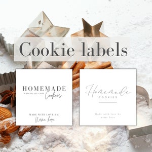 May include: Two white printable cookie labels with the text "Homemade Cookies" and "Made with love by: name here". The labels are on a white surface with cookie cutters and cinnamon sticks.