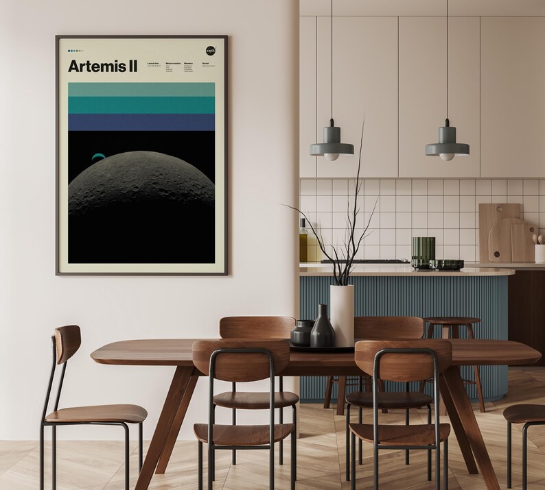May include: Framed art print featuring the text "Artemis II" with a NASA logo. The artwork depicts a celestial scene with a large, textured moon in the foreground, a smaller planet, and horizontal bands of teal and blue above.